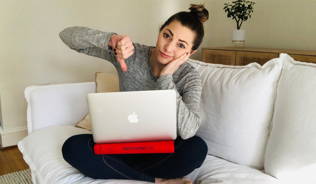 woman sitting on couch using a book as a lap desk