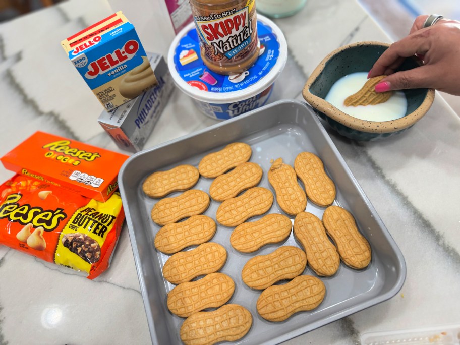 dunking nutter butters in milk and placing in a pan 