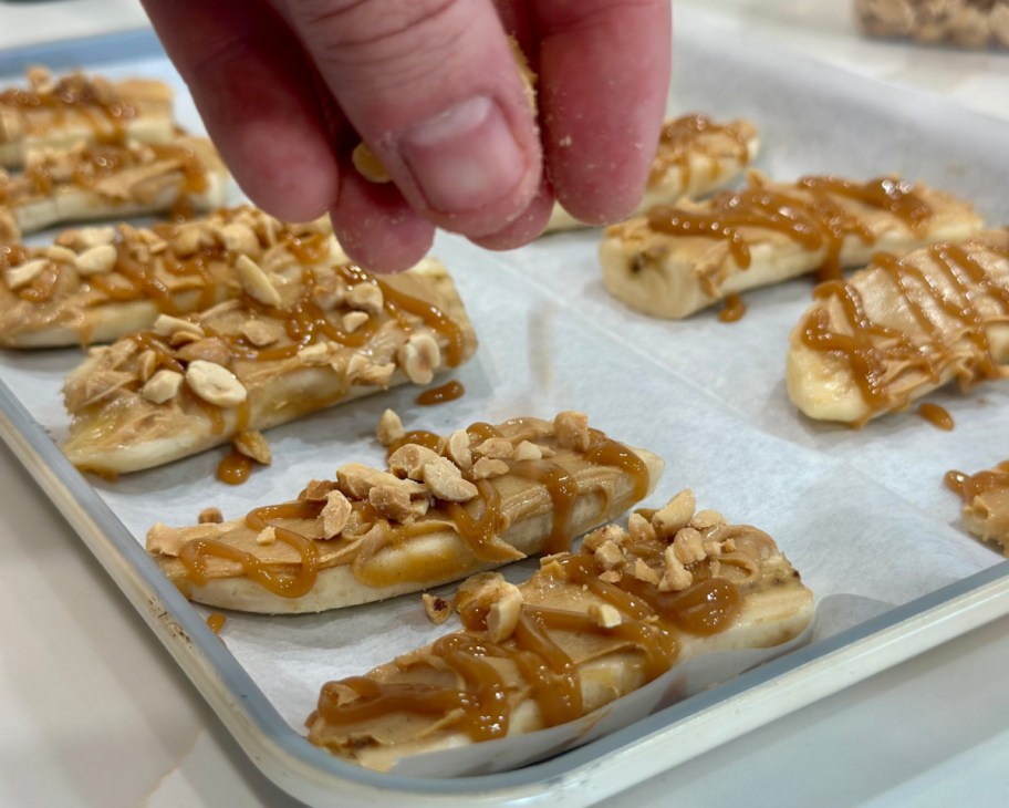hand sprinkling peanuts over bananas