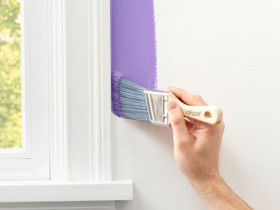 Hand using a Valspar Paint Brrush to paint around a window frame